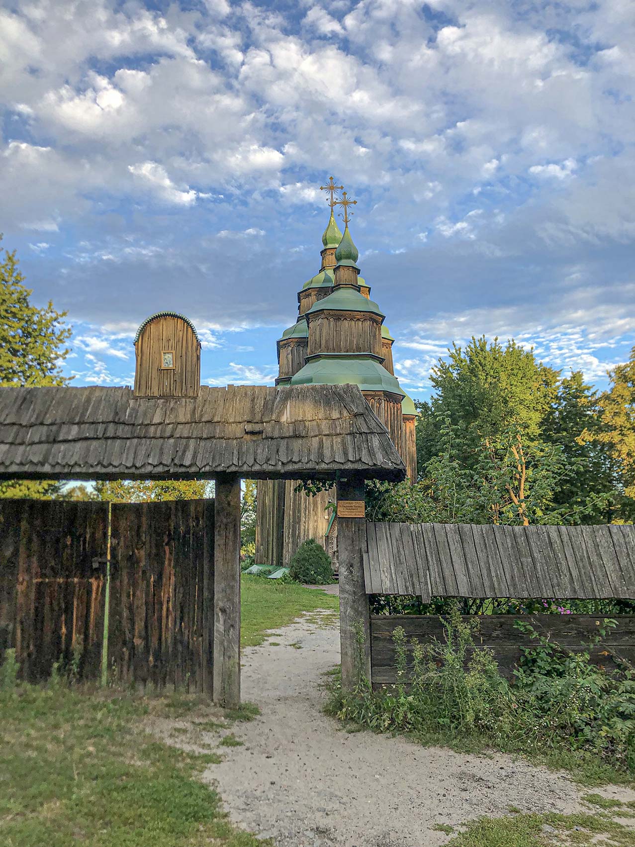 Навпроти входу у церкву ворота та двері, накриті дашком з іконою
